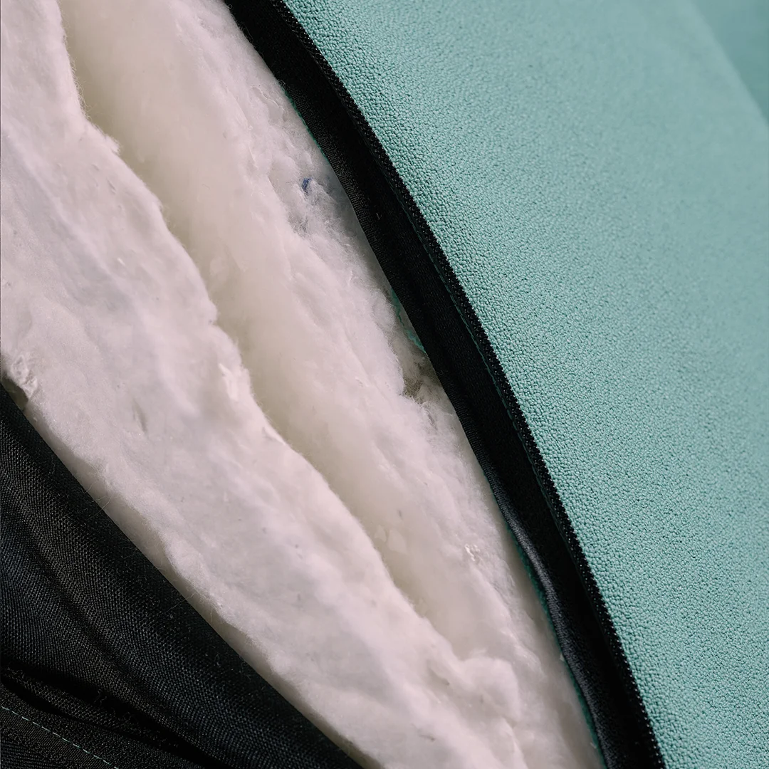 Close-up of a zippered seat cushion revealing its inner recycled filling made from repurposed tobacco filters, with textured teal upholstery on the outside.