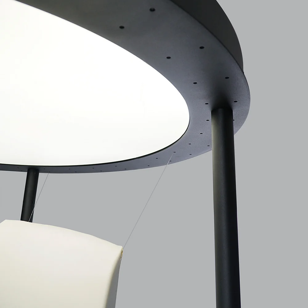 Detail of circular display structure with suspended Terra Lounge chair component, showing the metal frame and overhead lighting ring.