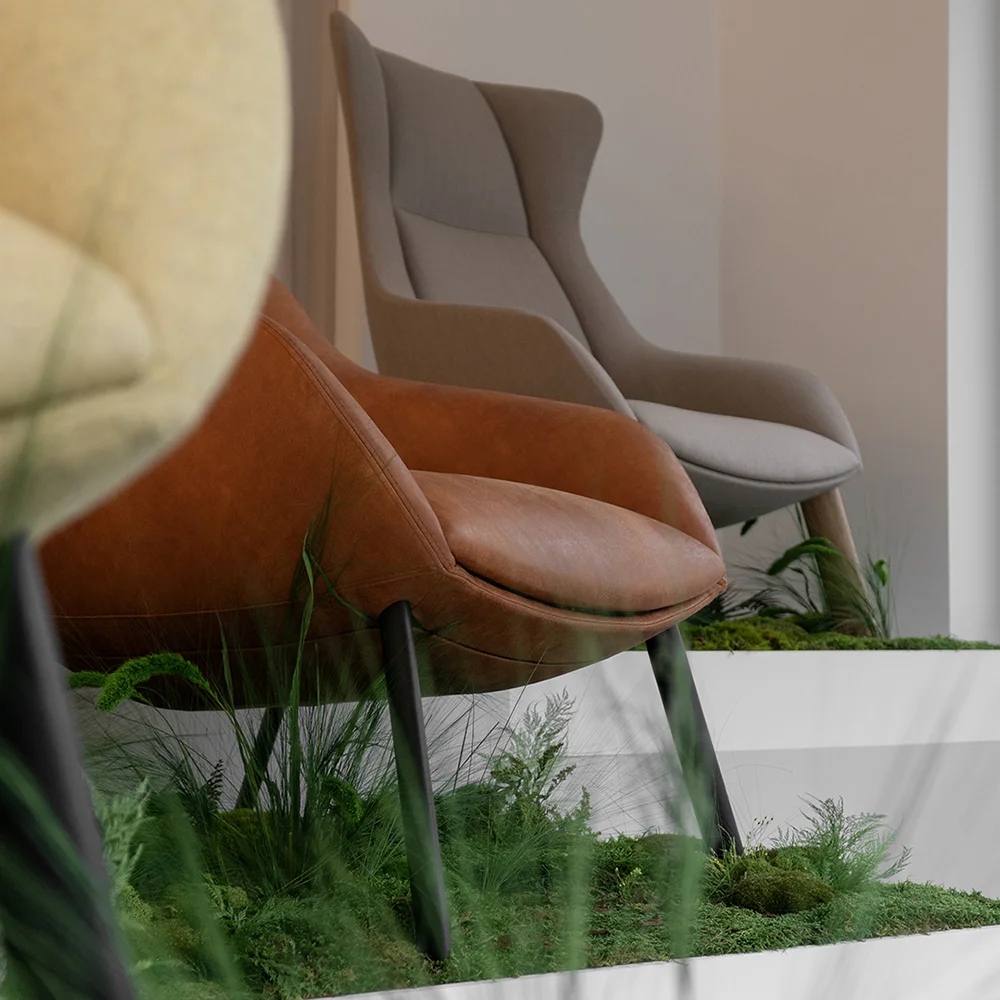 Close-up of Terra Lounge armchairs with soft upholstery and curved forms, set on tiered platforms with moss and grasses, highlighting the natural installation detail.