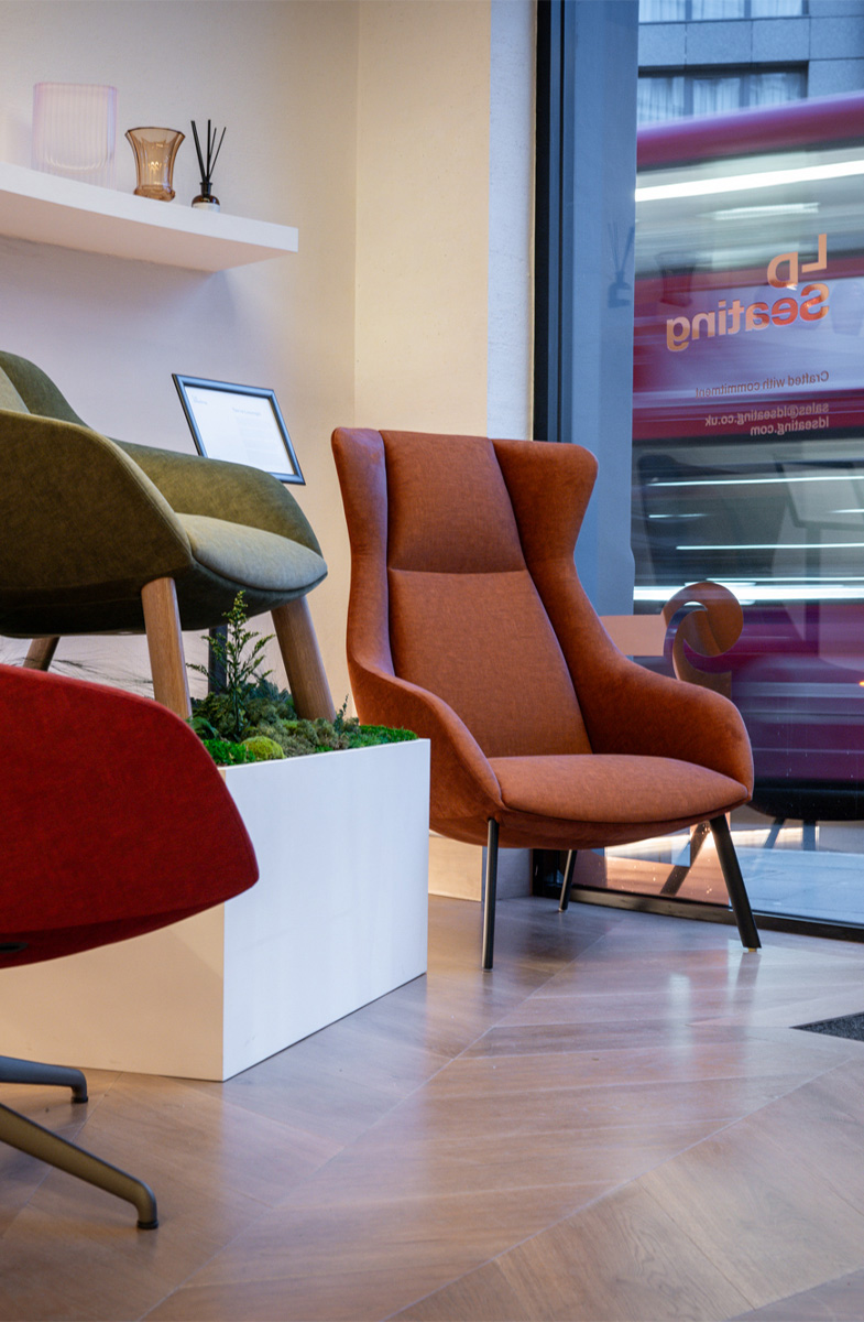 Three Terra Lounge armchairs in different colours displayed in the LD Seating London showroom beside a large street-facing window with passing city traffic outside.