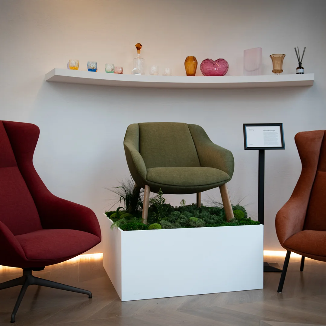 Three Terra Lounge armchairs in different colours displayed around a planted installation in the LD Seating London showroom.