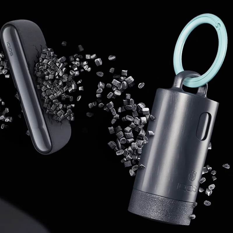 IQOS Clip Case with a turquoise carabiner shown among recycled plastic pellets and IQOS devices on a dark background.