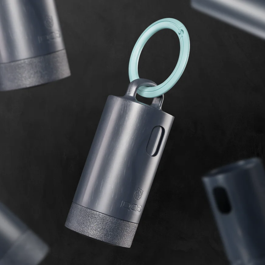 Anthracite IQOS Clip Case with an IQOS Turquoise carabiner, shown alongside additional cases on a dark background.