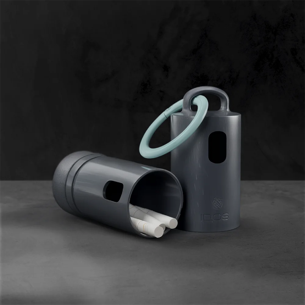 Two Anthracite IQOS Clip Cases, one open with used IQOS sticks inside and one upright with a turquoise carabiner attached.